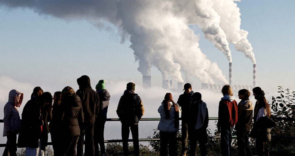 People watch smoke and steam billow from Belchatow Power Station