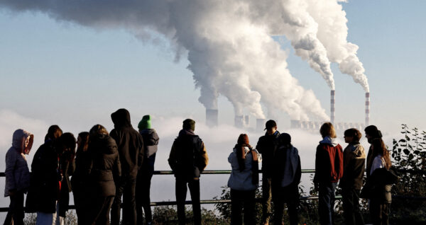 People watch smoke and steam billow from Belchatow Power Station