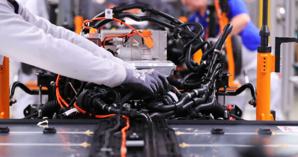 An employee connects cables between an electric motor and lithium-ion automotive battery on the Volkswagen AG (VW) ID.3 electric automobile assembly line