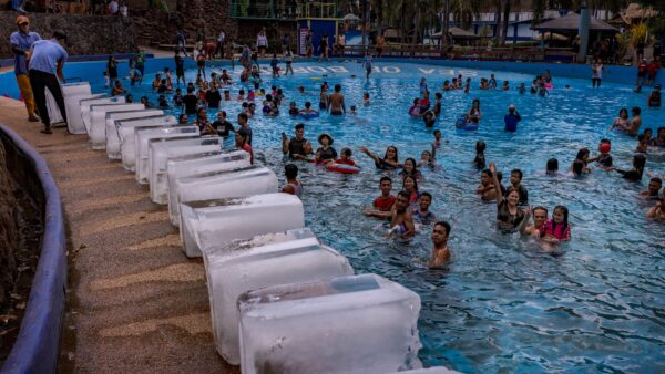 Workers at a resort prepare to dump blocks of ice in a swimming pool amid extreme heat in the Philippines. provinces